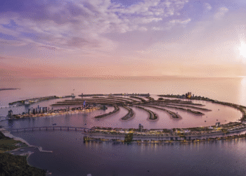 Aerial view of Palm Jebel Ali in Dubai at sunset, showing the fronds, waterfront skyline, and expansive coastline.