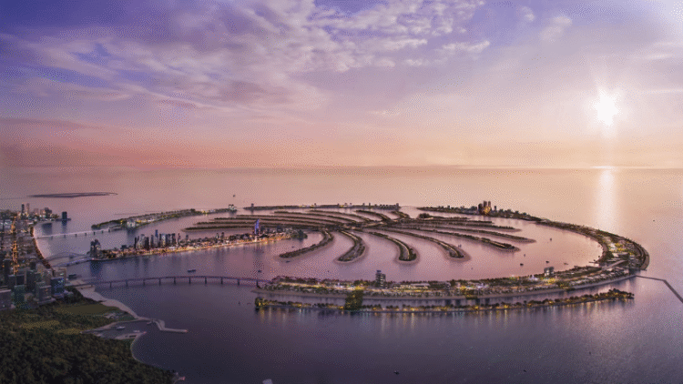 Aerial view of Palm Jebel Ali in Dubai at sunset, showing the fronds, waterfront skyline, and expansive coastline.