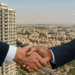 Business handshake between NiFCO and BNW with Jumeirah Village Circle skyline in the background.