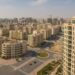 Jumeirah Village Circle (JVC) in Dubai with modern residential towers, villas, landscaped roads, and skyline in the background — real estate community view.