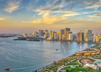 A wide-angle editorial photograph of Sharjah’s skyline featuring mid-rise residential buildings and active urban communities, reflecting the emirate’s expanding housing market.