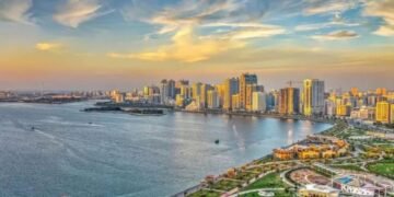 A wide-angle editorial photograph of Sharjah’s skyline featuring mid-rise residential buildings and active urban communities, reflecting the emirate’s expanding housing market.