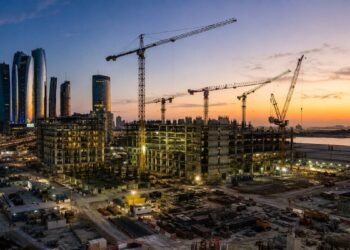 Construction cranes over an emerging UAE real estate development at dusk, reflecting the developer shift toward recurring income assets in 2026