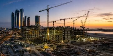 Construction cranes over an emerging UAE real estate development at dusk, reflecting the developer shift toward recurring income assets in 2026