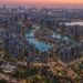 Aerial view of a Dubai master-planned mega project district with residential towers, lagoons and green public spaces at dusk