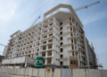 Azizi Beach Oasis II low-rise blocks under construction in Dubai Studio City, October 2026, with façade work still under way. Commission or request a current site photo from Azizi; avoid launch renders, which show a finished building the story says is not yet close.