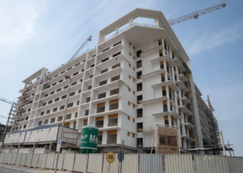 Azizi Beach Oasis II low-rise blocks under construction in Dubai Studio City, October 2026, with façade work still under way. Commission or request a current site photo from Azizi; avoid launch renders, which show a finished building the story says is not yet close.