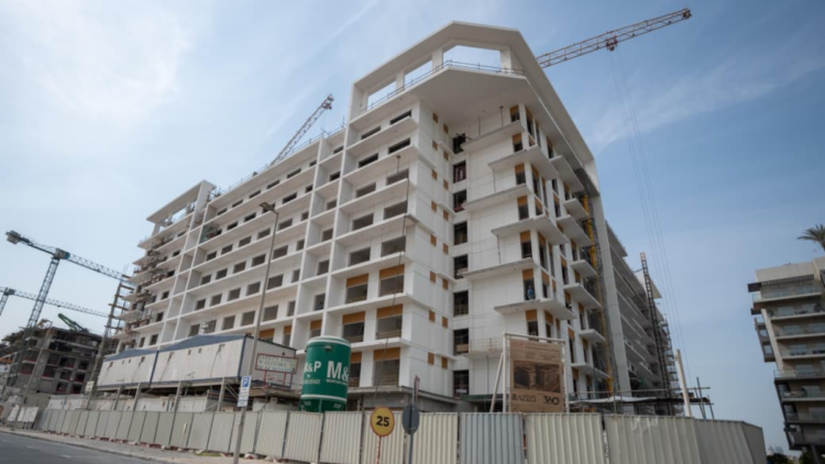 Azizi Beach Oasis II low-rise blocks under construction in Dubai Studio City, October 2026, with façade work still under way. Commission or request a current site photo from Azizi; avoid launch renders, which show a finished building the story says is not yet close.